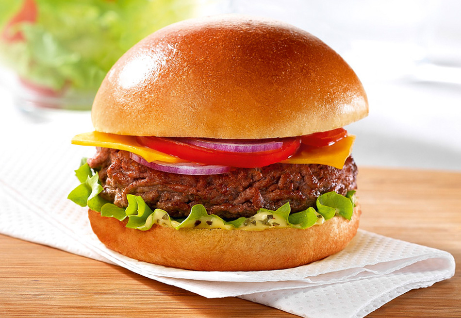 A Classic Brioche Cheeseburger recipe on top of kitchen roll on a wooden board