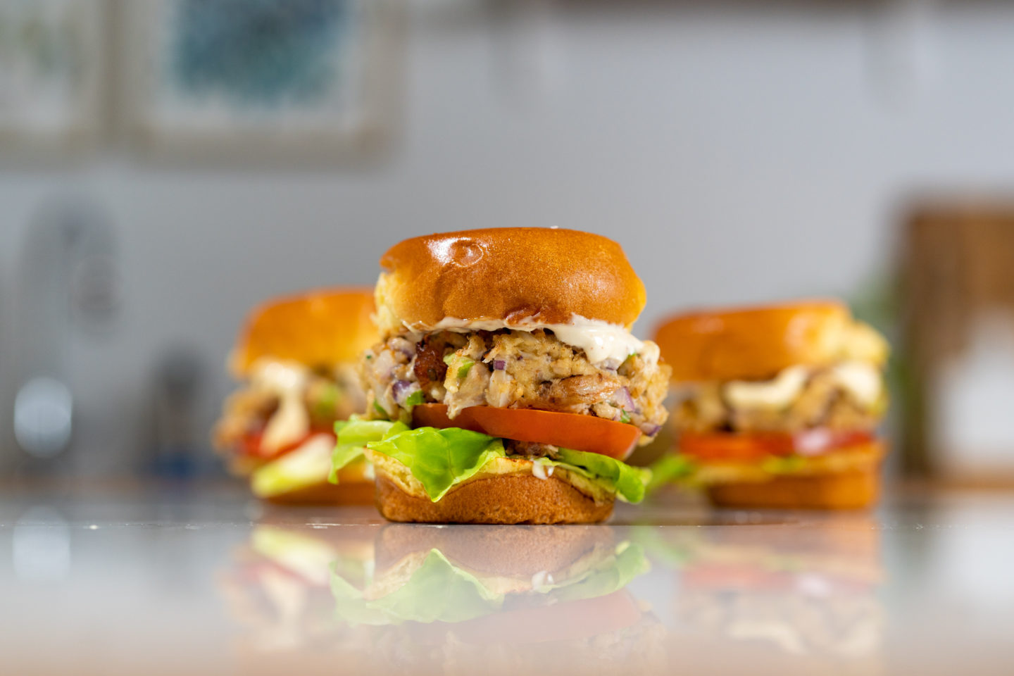 A photo of three small crab cake burgers on a table